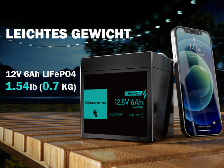 Black battery pack with digital display next to a smartphone on a wooden surface at night.