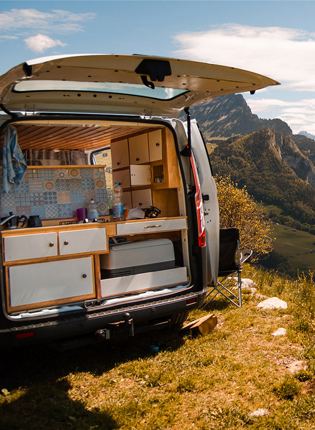 Van conversion with kitchen setup in a mountainous landscape