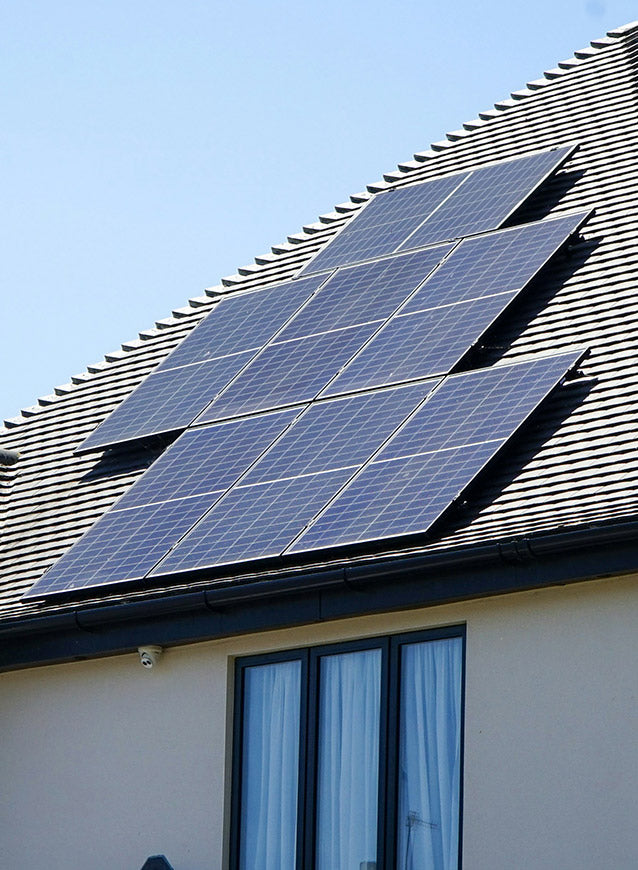 Solar panels on a house roof with a clear blue sky.